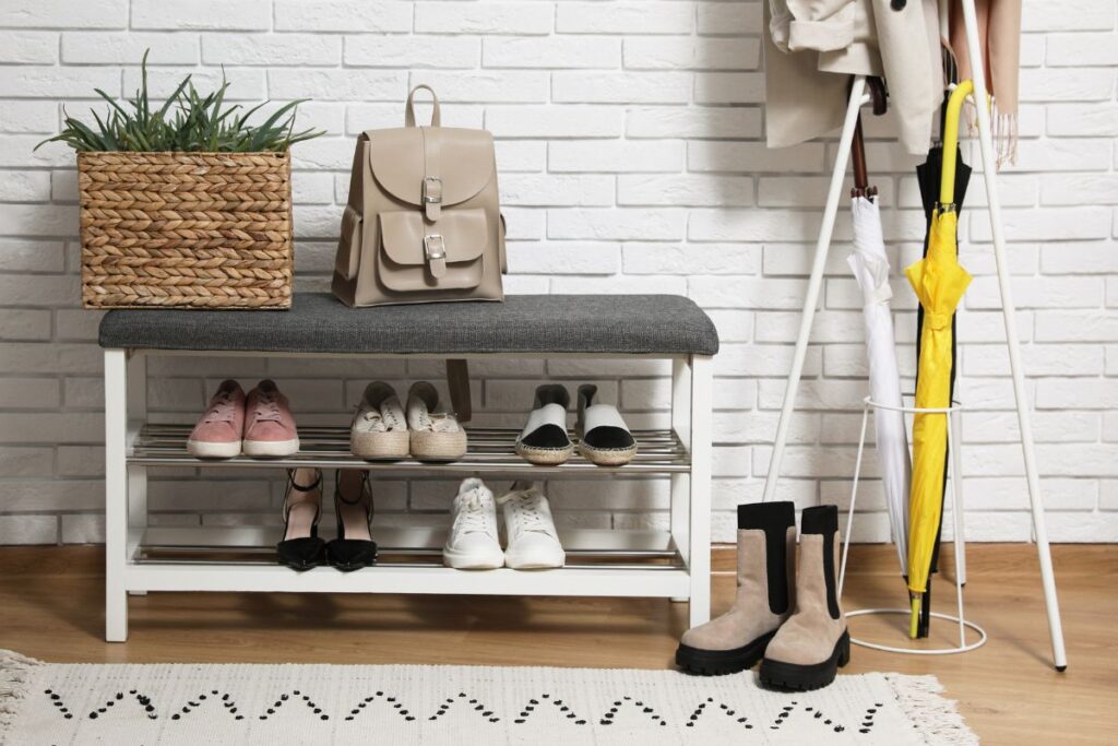 Sapateira branca organizada na entrada da casa com prateleiras e cestos decorativos