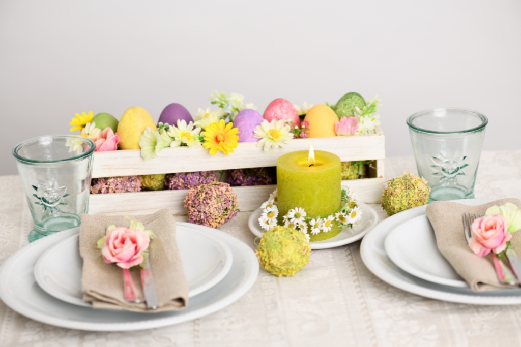 Mesa posta de Páscoa simples e elegante com ovos coloridos, vela decorativa e flores sobre mesa clara