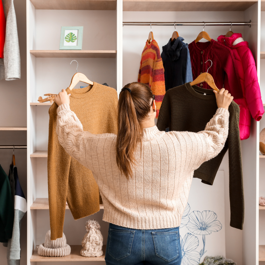 Mulher separando roupas que não usa mais no guarda-roupa